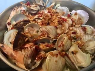 一锅出海鲜烩,打开平底锅盖，均匀地码上贝壳与章鱼，酱汁均匀地倒在面上。