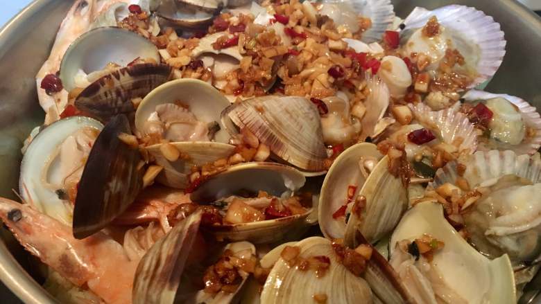 一锅出海鲜烩,打开平底锅盖，均匀地码上贝壳与章鱼，酱汁均匀地倒在面上。