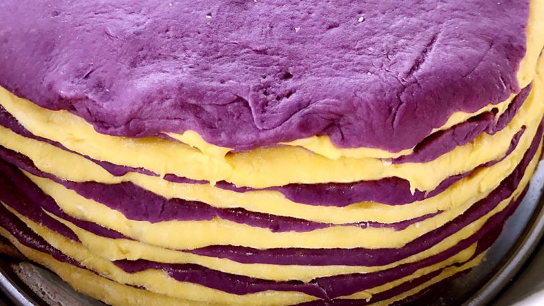 紫薯南瓜发糕,将面团擀成8寸磨具大小的圆饼状，颜色交错，叠放整齐，二次发酵20分钟