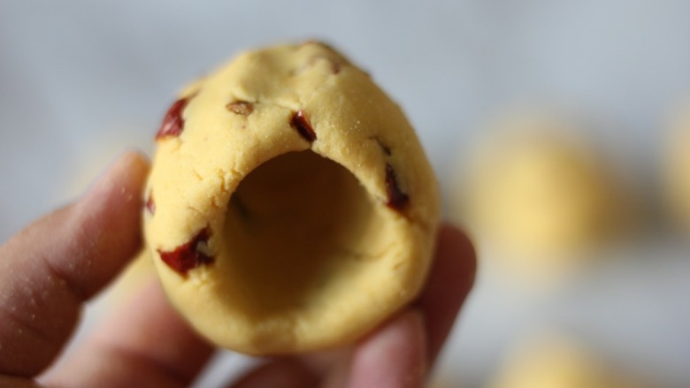 红枣奶香窝头,用大拇指一边在面团上钻洞，一边转动面团。