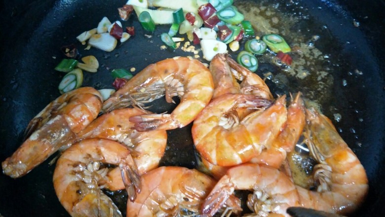 油焖大虾,虾炒红以后，铲到锅边，留个位置放入葱姜蒜和辣椒段炒香。