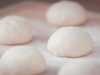红豆面包,和好的面团静置发酵50分钟，分割成每份50克的小面团，轻轻揉圆排气，静置15分钟，让面团稍微松弛下来，以便面包成型；