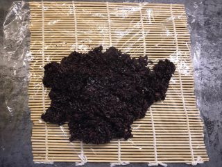 紫米粢饭团,寿司帘上铺上保鲜膜，将紫米放在保鲜膜上