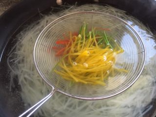 五彩缤纷凉拌土豆丝,放入土豆丝，在把三色丝放在漏勺里烫一下。