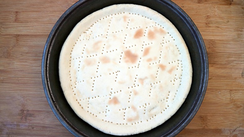 培根口蘑芝香披萨,披萨饼胚放入披萨盘中。（披萨饼胚的制作可参考我的菜谱八寸披萨饼胚的制作）