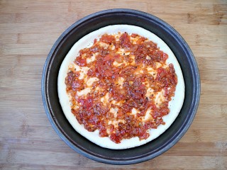 培根口蘑芝香披萨,把披萨酱（披萨酱可参考我的菜谱披萨酱的制作）均匀的涂抹在披萨饼胚上。