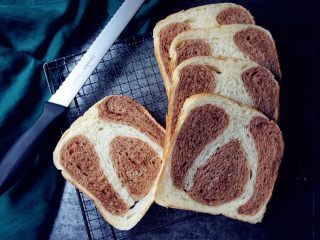 面包机版双味吐司,烘烤结束，立即将面包桶提出来，将面包放在晾架上晾凉，待晾凉后切片。未食用的面包需放进保鲜袋里，扎紧口袋，室温保存即可