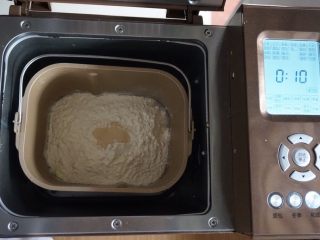 面包机版双味吐司,倒入面粉，在面粉顶端加入酵母，将面包桶放入到东菱1352-AE面包机里，启动面包机的和面程序10分钟