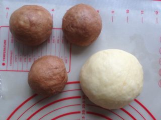 面包机版双味吐司,发酵好的面团，用手掌按压排气，可可面团分成3等份，全部滚圆，盖上保鲜膜静置15分钟