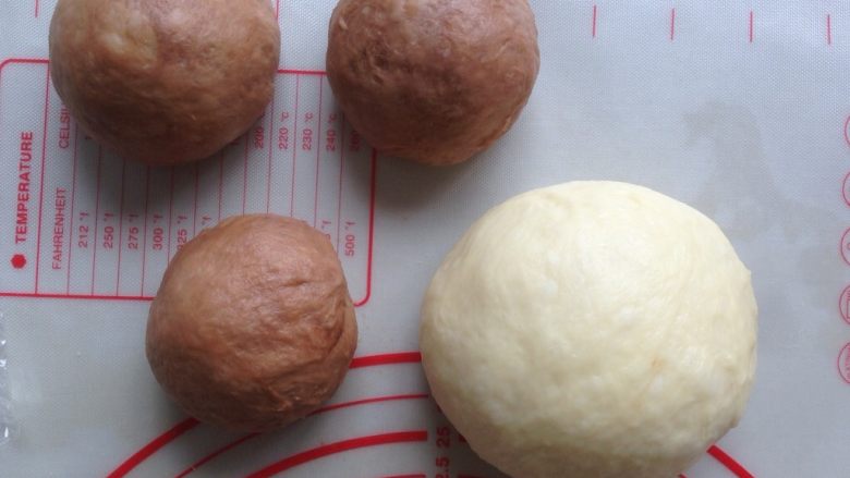 面包机版双味吐司,发酵好的面团，用手掌按压排气，可可面团分成3等份，全部滚圆，盖上保鲜膜静置15分钟