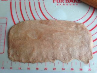 面包机版双味吐司,可可面团擀成椭圆形，其中一条边擀薄