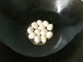 鹌鹑蛋烧豆腐,锅中入少许油，下入鹌鹑蛋，再加入一勺料酒翻炒一下；