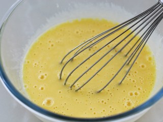 中空戚风蛋糕(7寸),蛋黄打散后加入25克细砂糖、玉米油和纯牛奶搅拌均匀