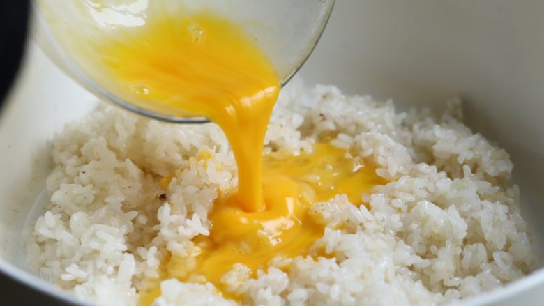 缤纷虾仁蛋炒饭,将打散的蛋液均匀倒入米饭，大火迅速翻炒，使蛋液与米饭相互粘合。