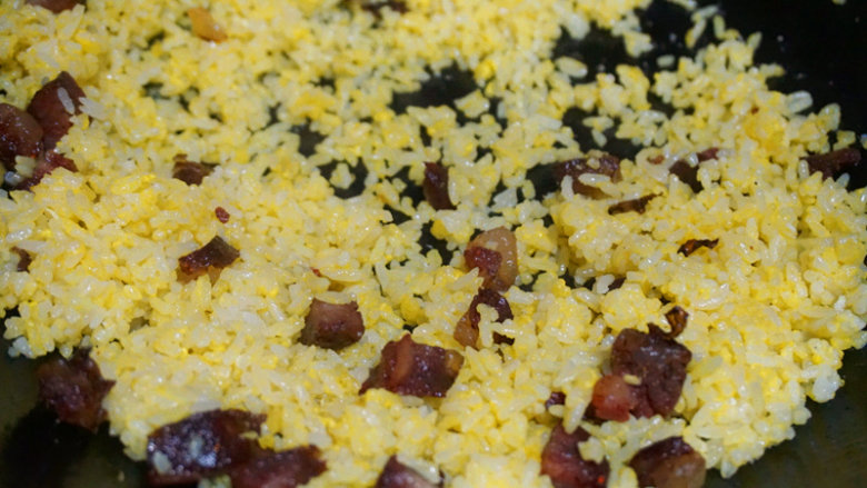 黄金蛋炒饭,待蛋黄完全包裹住米饭后，下入刚刚炒好的腊肠丁拌匀