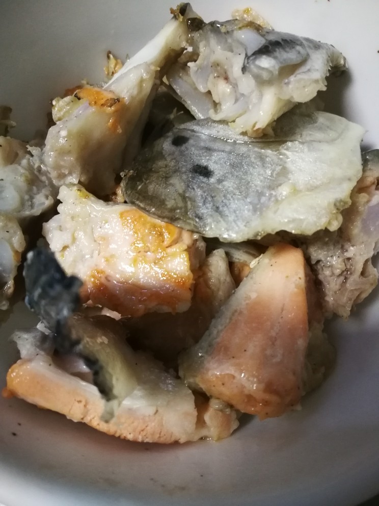 三文鱼头豆腐煲,煎好的鱼头块捞出。