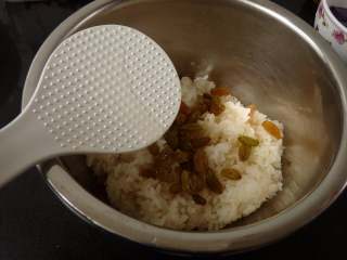 桂花紫薯糯米饭,煮熟的糯米饭趁热加入洗净的葡萄干与茶油
