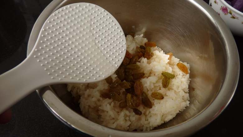 桂花紫薯糯米饭,煮熟的糯米饭趁热加入洗净的葡萄干与茶油