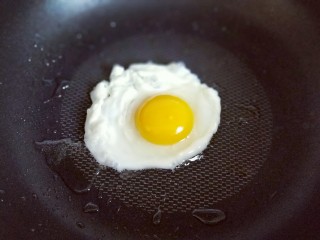 韩式石锅拌饭,煎荷包蛋，油温8成时加入鸡蛋，可以用铲子稍做整形，煎至蛋白凝固即可。