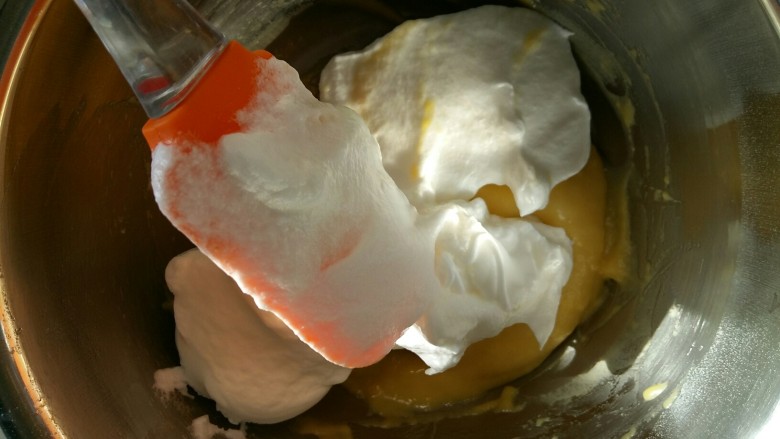 戚风杯子蛋糕,取1/2蛋白加入蛋黄糊中，用切拌的手法拌匀。