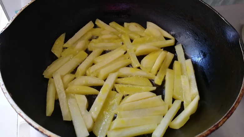 腊肠炒土豆条蒜苔,油热放入土豆条（油是平时炒菜的2倍）
