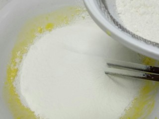 自制芝麻蛋糕,低筋面粉过筛加入蛋黄液中，搅拌至蛋黄和面粉完全混合在一起。
