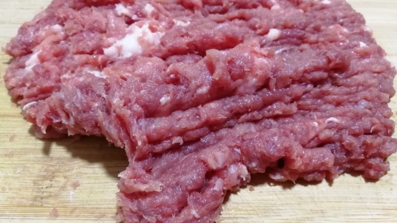 吉利蒸肉丸,猪肉放在案板上剁成肉糜状。
