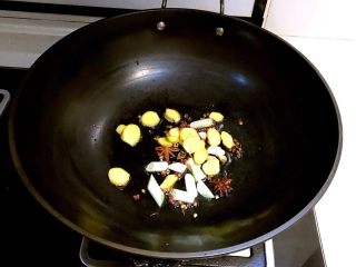 红烧猪尾,加入葱段和姜片，翻炒1分钟