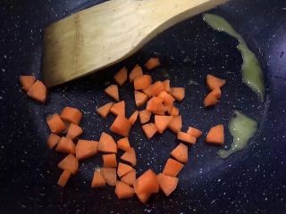 香甜牛奶南瓜焖饭,将胡萝卜洗净去皮切丁放入锅中