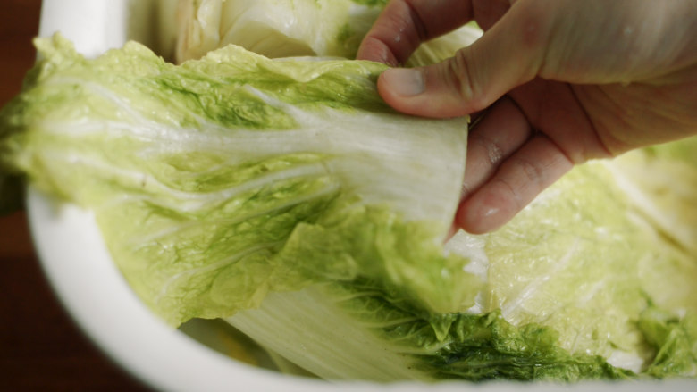 制作自家口味的韩式泡菜,将盐分充分洗掉。把白菜从根部的切口撕开。