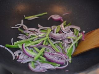 茄汁牛肉意面,锅中留底油烧热，放入洋葱和青椒翻炒片刻。
