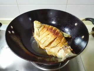 糖醋胡萝卜鳊鱼,调大火煎一分钟，再调中火，转动锅，使鱼各个部位都煎到，煎到金黄色，鱼在锅里移动就可以翻面，再煎