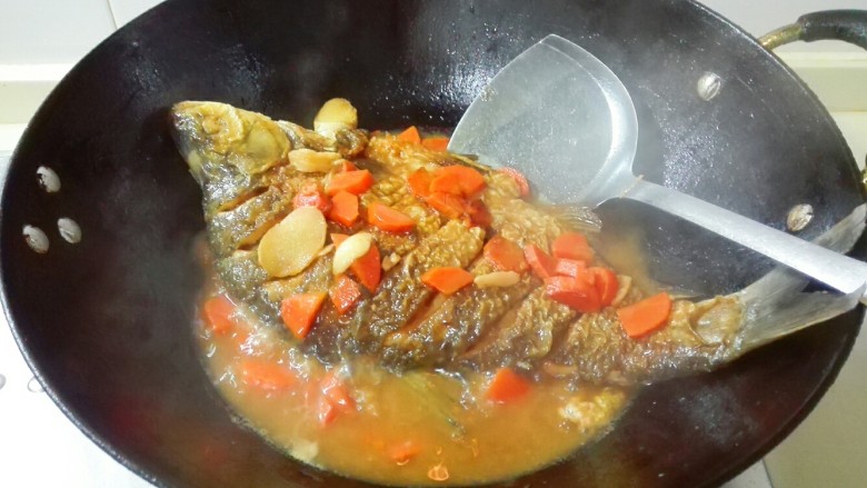 糖醋胡萝卜鳊鱼,调大火收汁，用锅铲把汤汁往鱼身上浇一浇