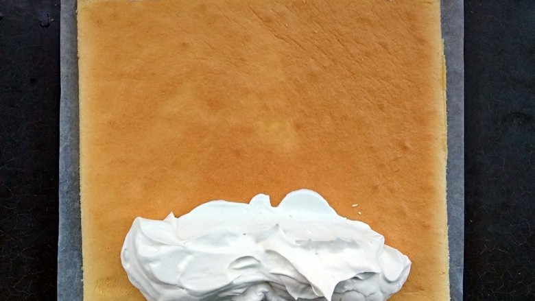 毛巾面蛋糕卷,把奶油都堆在要卷的这边，尾部稍微涂一点就ok。卷的时候需要借助擀面棍，而且也需要一张够长的油纸来辅助卷。