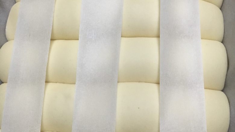 #最爱面包#奶酪夹馅排包,发酵至两倍大，裁三条一样宽的纸平均放在表面