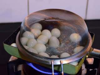 鹌鹑蛋宝宝和它的蔬菜朋友们,倒入鹌鹑蛋，转小火慢慢炸。此时将滤网罩在油锅上，可以防止油滴飞溅——很实用的小妙招哦！