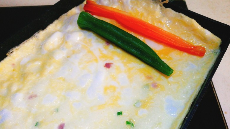 阳光早餐～秋葵厚蛋烧,将秋葵和胡萝卜条放在蛋饼一边