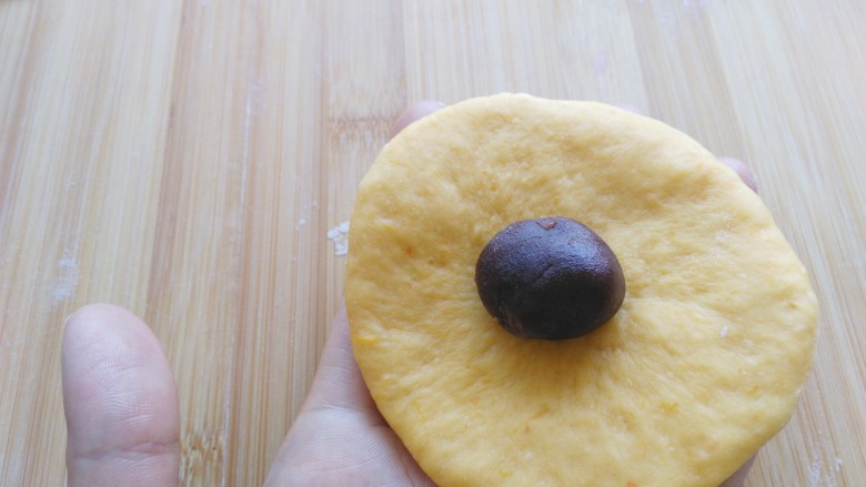 #感恩节食谱#南瓜豆沙面包,将每一份小面团压扁，放入豆沙馅儿。