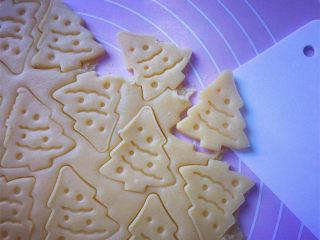 圣诞树饼干,小心去掉周边的面片，（去掉的面片还可以重复擀开使用）然后用刮刀移铲到不粘烤盘上。