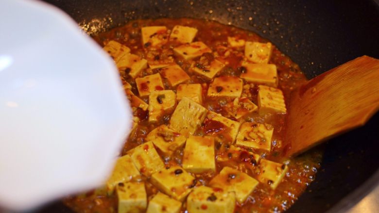正宗地道的麻婆豆腐,煮到还剩少量汤汁时，倒入水淀粉。用铲子轻推。