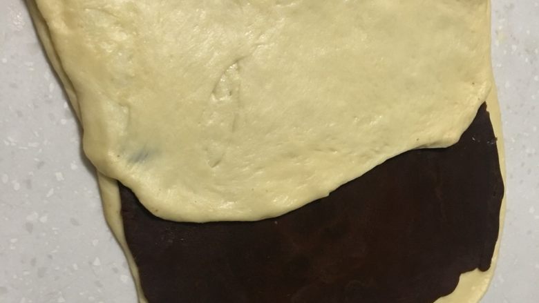 大理石纹豆沙吐司,叠被子的方法将空白面皮叠起来，盖住豆沙面皮的一半。