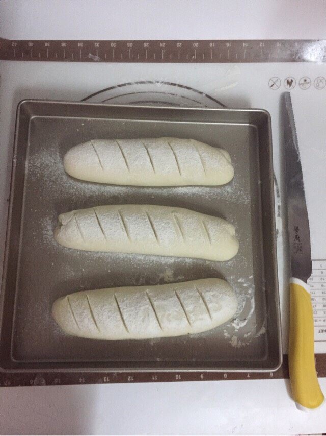 法棍面包,放置温暖处，发酵至原来的两倍大。筛上一层面粉。用刀子割出小口。
