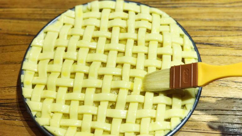 披萨模具也能做的酥皮苹果派,此时可预热烤箱，上下火200度15min。在编织好的派皮上刷上一层蛋液