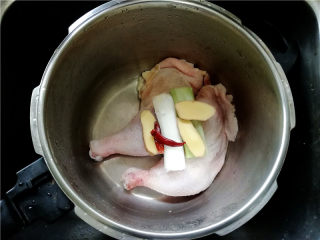 泰国鱼露鸡,取一炖锅，将鸡腿、葱姜、干红椒放入锅中。