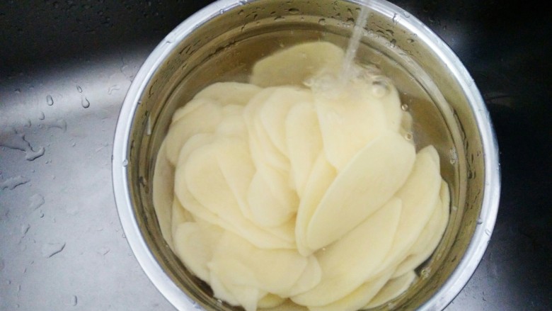 #圆土豆#香辣脆薯片,切好的土豆片在流动水下冲洗两遍，去除土豆表面多余的淀粉。