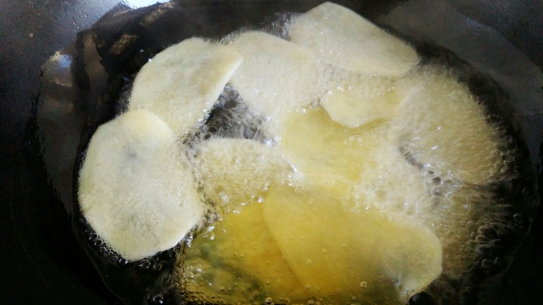 #圆土豆#香辣脆薯片,油温六、七成热后，下入控干水的土豆片，进行炸制，全程小火。