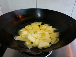 五花肉酱炒土豆片,锅里倒入适量油烧热，放入沥干水的土豆片小火炸至