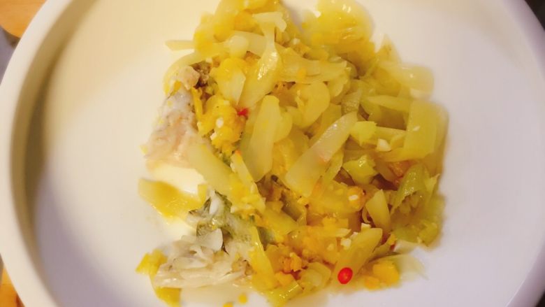 金椒酸汤鲈鱼,把锅里的鱼骨酸菜用漏勺捞出放入汤盆中，再用细漏勺把残渣捞出扔掉