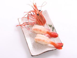 自制手握牡丹虾寿司,在牡丹虾背部蘸少许青芥，然后与整形好的饭团放在一起进行最后一次塑形即可入盘了
