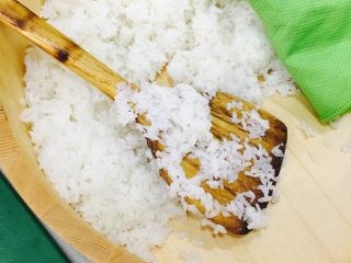 自制手握牡丹虾寿司,米饭出锅后放入木盆中，浇入1/3寿司醋，用木勺翻拌入米饭中，用屉布盖上静置10分钟